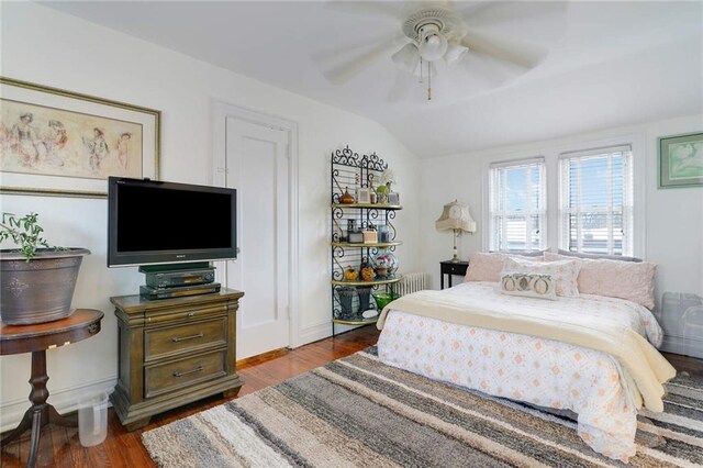 bedroom featuring a ceiling fan, vaulted ceiling, wood finished floors, and baseboards