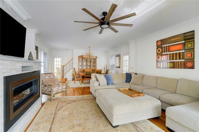 living room featuring ornamental molding, ceiling fan with notable chandelier, and light wood-type flooring