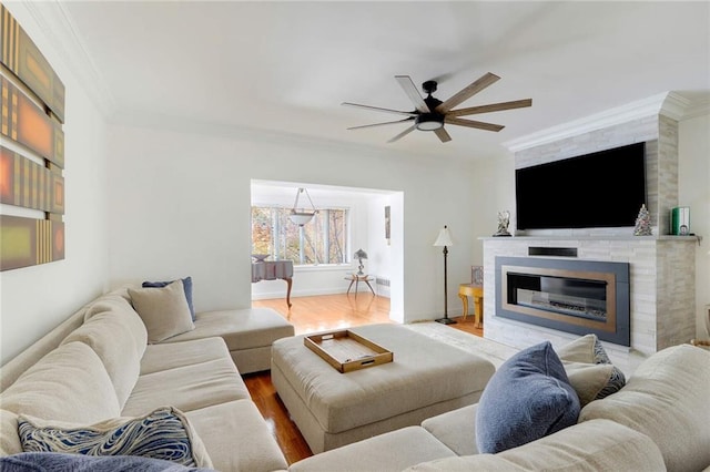 living room with a fireplace, hardwood / wood-style flooring, ceiling fan, and crown molding