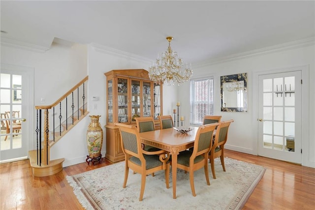 dining space with stairway, light wood-style flooring, crown molding, and an inviting chandelier