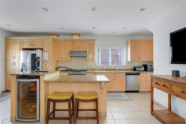 kitchen featuring under cabinet range hood, wine cooler, appliances with stainless steel finishes, and light brown cabinetry