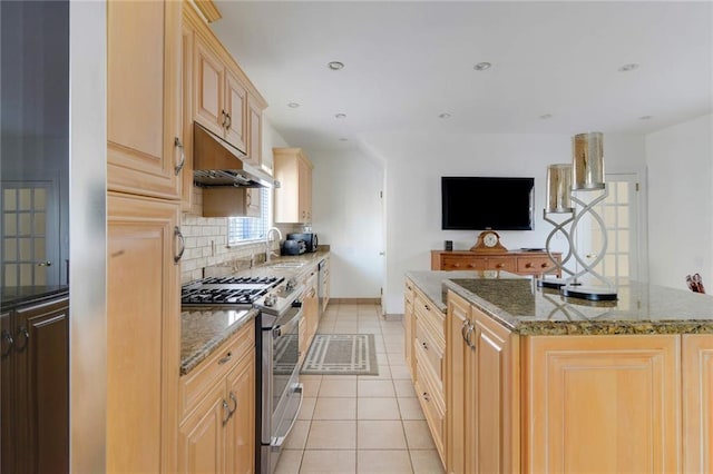 kitchen featuring stainless steel gas range oven, a kitchen island with sink, under cabinet range hood, tasteful backsplash, and light tile patterned floors