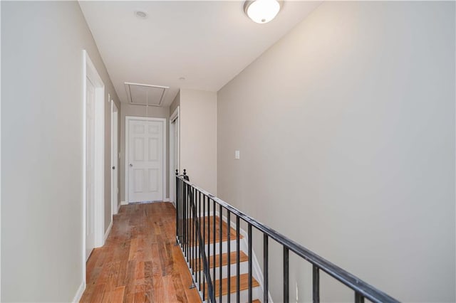 corridor with light wood-type flooring, baseboards, and attic access