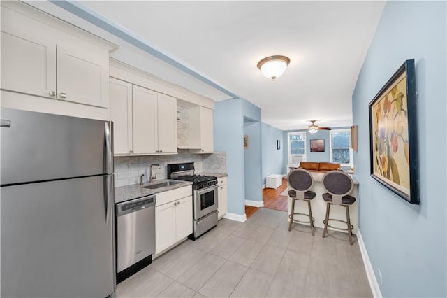 kitchen with sink, ceiling fan, appliances with stainless steel finishes, tasteful backsplash, and white cabinets