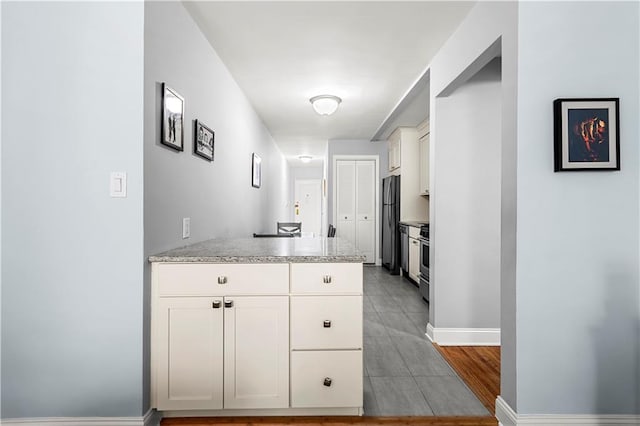 kitchen featuring white cabinetry, appliances with stainless steel finishes, light stone countertops, and light tile patterned floors