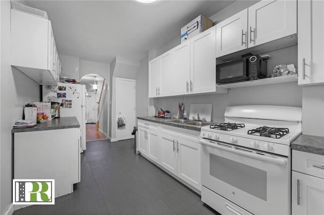 kitchen featuring arched walkways, white appliances, white cabinets, and a sink