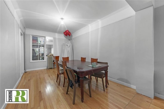 dining space featuring light wood-type flooring, radiator heating unit, and baseboards