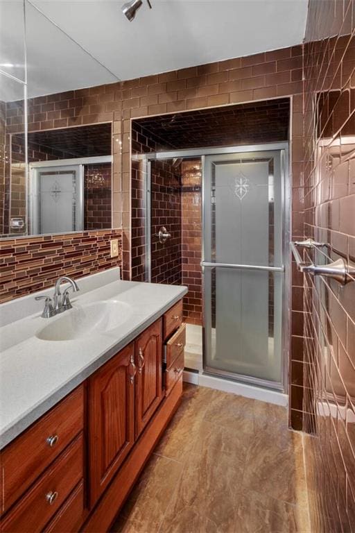 full bath with tile walls, a shower stall, and vanity