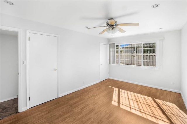 unfurnished bedroom with ceiling fan, wood finished floors, and baseboards