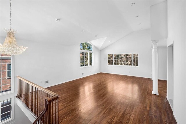 unfurnished living room featuring a chandelier, dark hardwood / wood-style floors, vaulted ceiling, and decorative columns