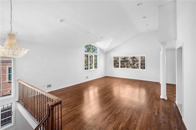 unfurnished living room featuring ornate columns, lofted ceiling, dark wood-type flooring, and a chandelier