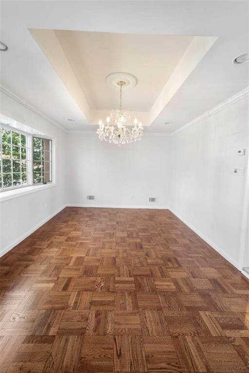 spare room featuring ornamental molding, dark parquet flooring, a raised ceiling, and a notable chandelier