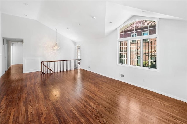 unfurnished room featuring baseboards, visible vents, vaulted ceiling, and dark wood finished floors