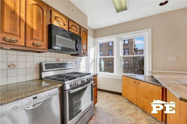 kitchen featuring appliances with stainless steel finishes, dark stone countertops, and backsplash