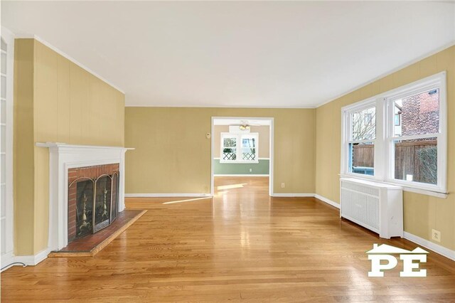 unfurnished living room featuring a fireplace, radiator, and light hardwood / wood-style flooring