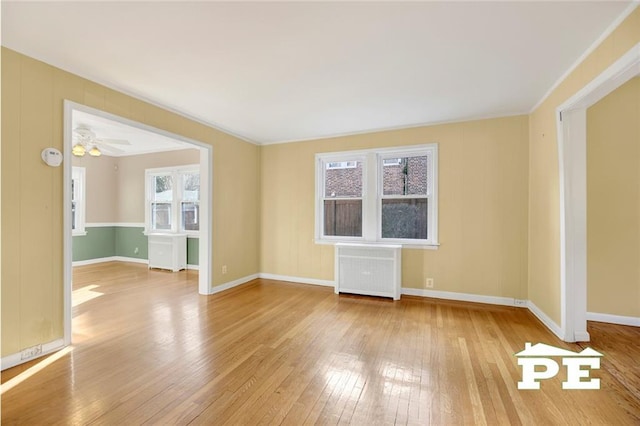 unfurnished room with radiator heating unit, ornamental molding, and light wood-type flooring