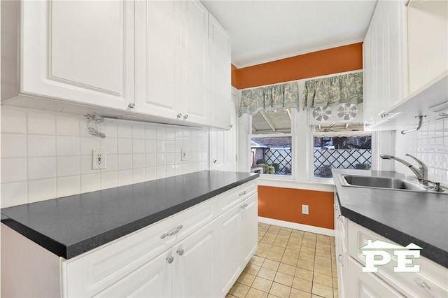 kitchen with tasteful backsplash, light tile patterned flooring, sink, and white cabinets