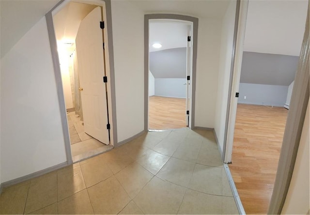 hallway featuring lofted ceiling and light tile patterned floors