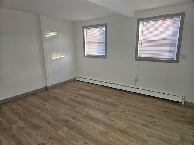 empty room featuring baseboard heating and hardwood / wood-style flooring