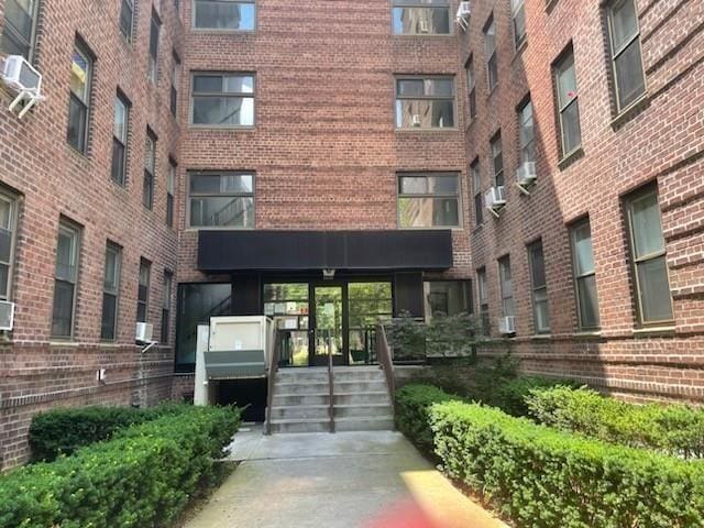 doorway to property with cooling unit, brick siding, and a wall mounted AC