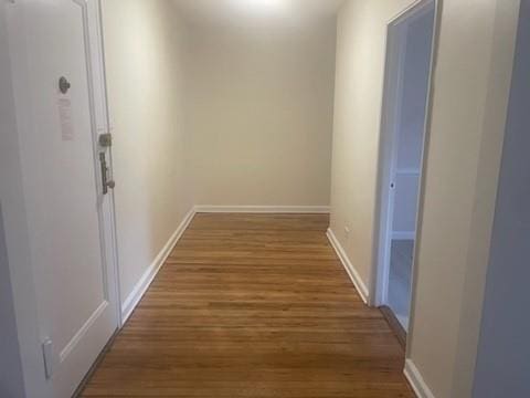 corridor with baseboards and wood finished floors