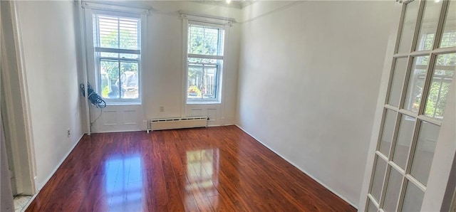 empty room featuring dark hardwood / wood-style flooring, plenty of natural light, and baseboard heating