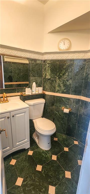 bathroom with vanity, tile walls, and toilet