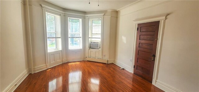 empty room featuring baseboard heating, cooling unit, and hardwood / wood-style flooring