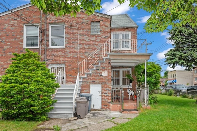 exterior space with stairs, a lawn, and brick siding