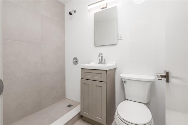 bathroom featuring toilet, vanity, and a tile shower