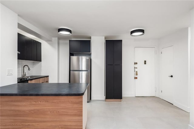 kitchen featuring sink, tasteful backsplash, and stainless steel refrigerator