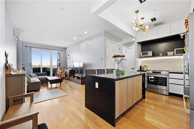 kitchen featuring a kitchen island, backsplash, a wall mounted AC, light hardwood / wood-style floors, and high end range