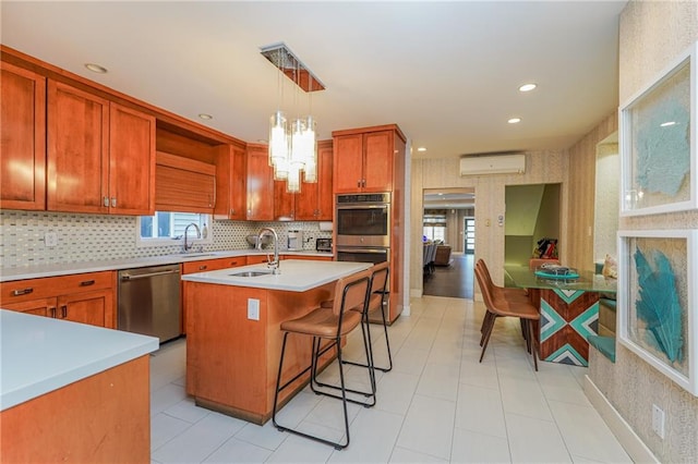 kitchen with a kitchen island with sink, stainless steel appliances, light countertops, a wall mounted air conditioner, and wallpapered walls