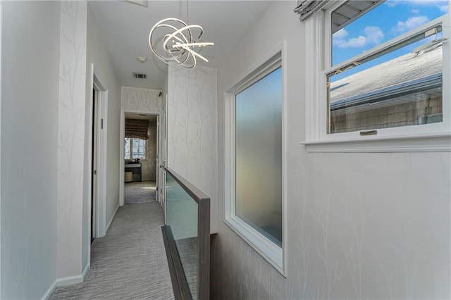 hall with visible vents, baseboards, wallpapered walls, carpet, and an inviting chandelier