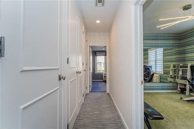 corridor featuring baseboards, carpet, visible vents, and wallpapered walls