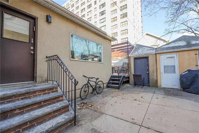 1469 E 5th St, Brooklyn, NY 11230 - view of exterior entry featuring stucco siding, a patio area, and a deck