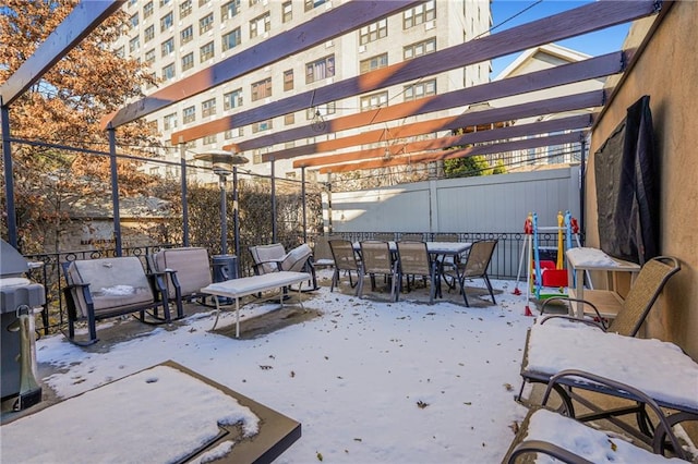 snow covered patio featuring fence, outdoor dining area, and a pergola