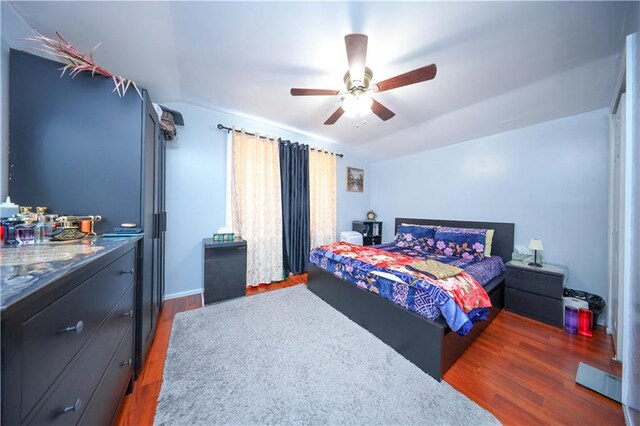 bedroom with a ceiling fan, lofted ceiling, and wood finished floors