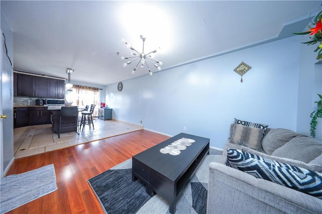 living room with baseboards, light wood finished floors, and an inviting chandelier