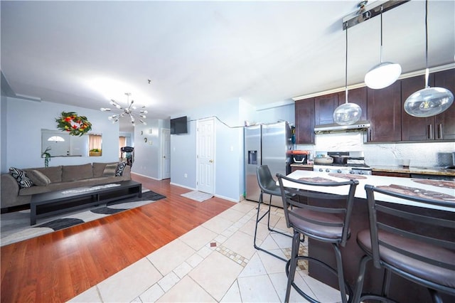 kitchen with stainless steel refrigerator with ice dispenser, light tile patterned floors, tasteful backsplash, dark brown cabinetry, and range