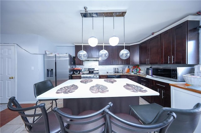 kitchen with a breakfast bar, light countertops, decorative backsplash, appliances with stainless steel finishes, and a kitchen island