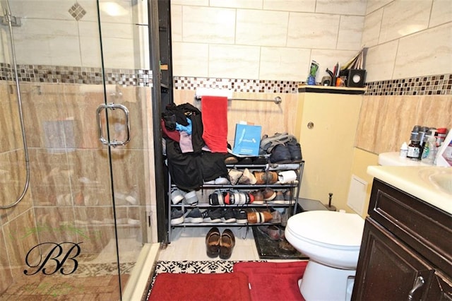 full bathroom with toilet, vanity, a shower stall, and tile walls