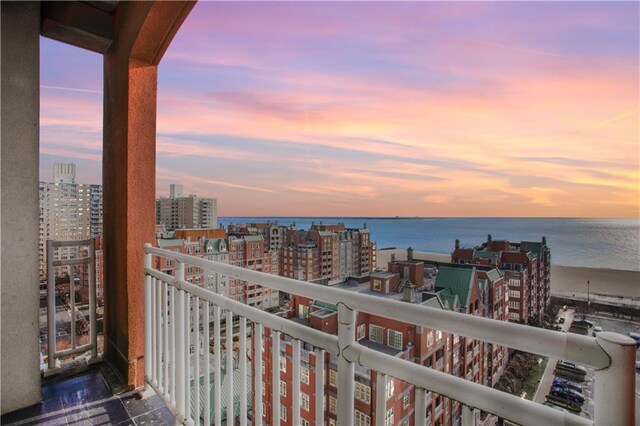 balcony at dusk featuring a water view