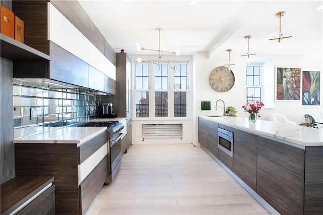 kitchen featuring pendant lighting, stainless steel appliances, an inviting chandelier, decorative backsplash, and sink