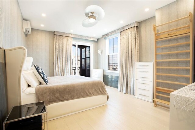 bedroom featuring a wall mounted AC, access to exterior, and hardwood / wood-style flooring