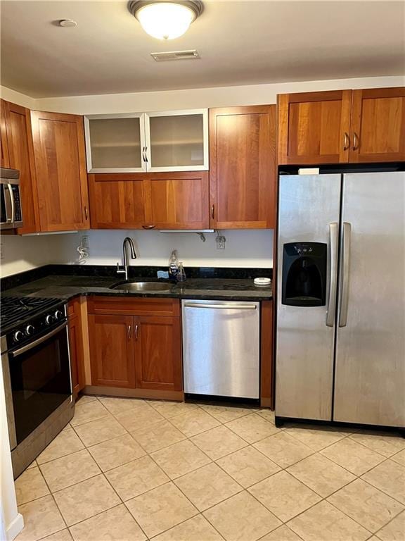 kitchen featuring brown cabinets, visible vents, appliances with stainless steel finishes, glass insert cabinets, and a sink