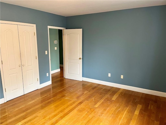 unfurnished bedroom featuring light wood-type flooring, a closet, and baseboards