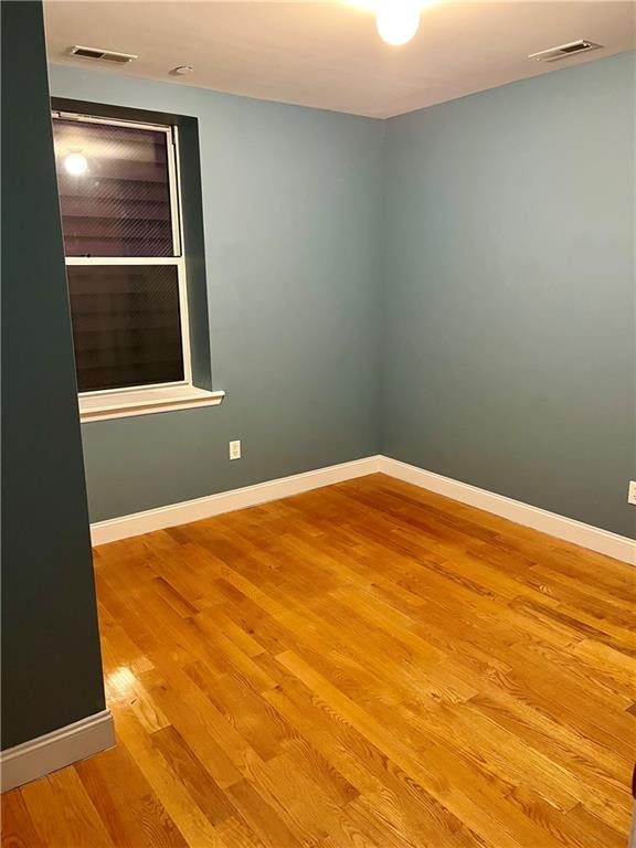 empty room featuring light wood-type flooring, visible vents, and baseboards