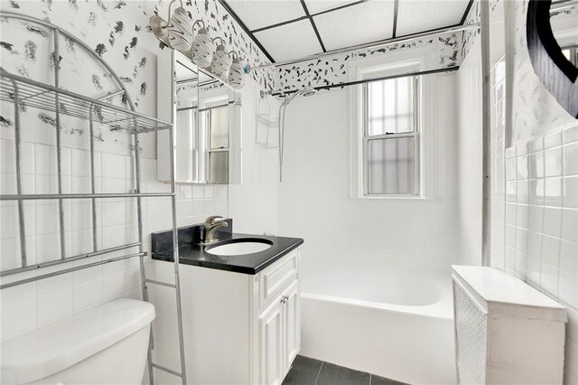 full bathroom with tile patterned floors, vanity,  shower combination, tile walls, and toilet