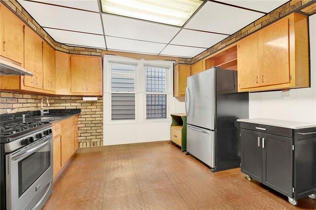 kitchen featuring a drop ceiling, sink, decorative backsplash, range hood, and appliances with stainless steel finishes